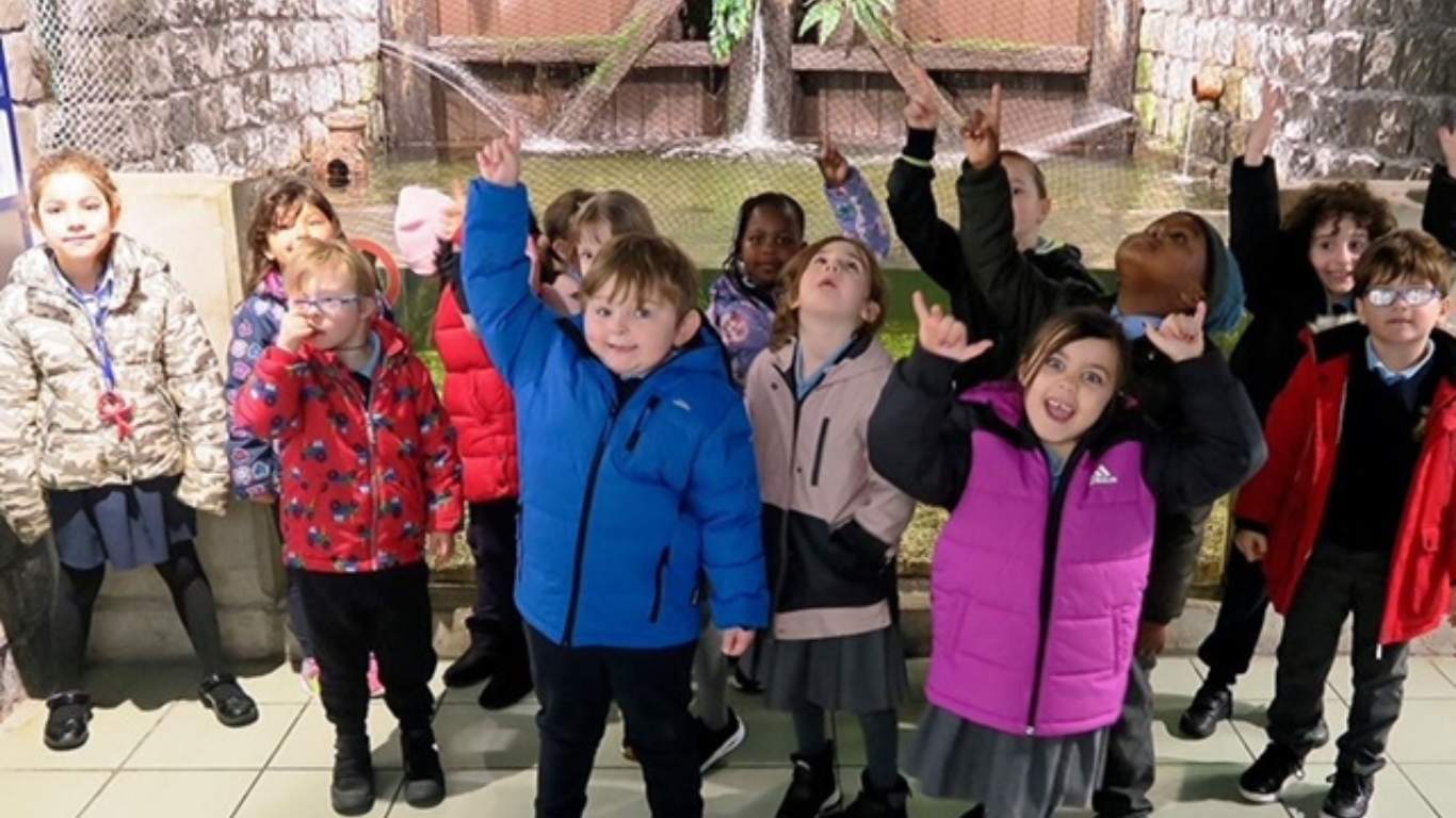 Students pointing to the fin whale skelleton at the aquarium during an aquarium tour.