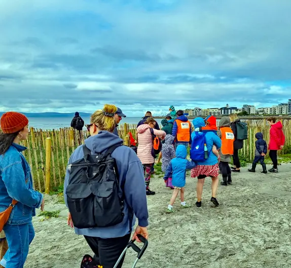 A large group of people walking to Grattan Beach in Salthill to do a seashore experience.