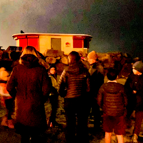 A group of adults and children on the beach in Salthill, listening for Bats.