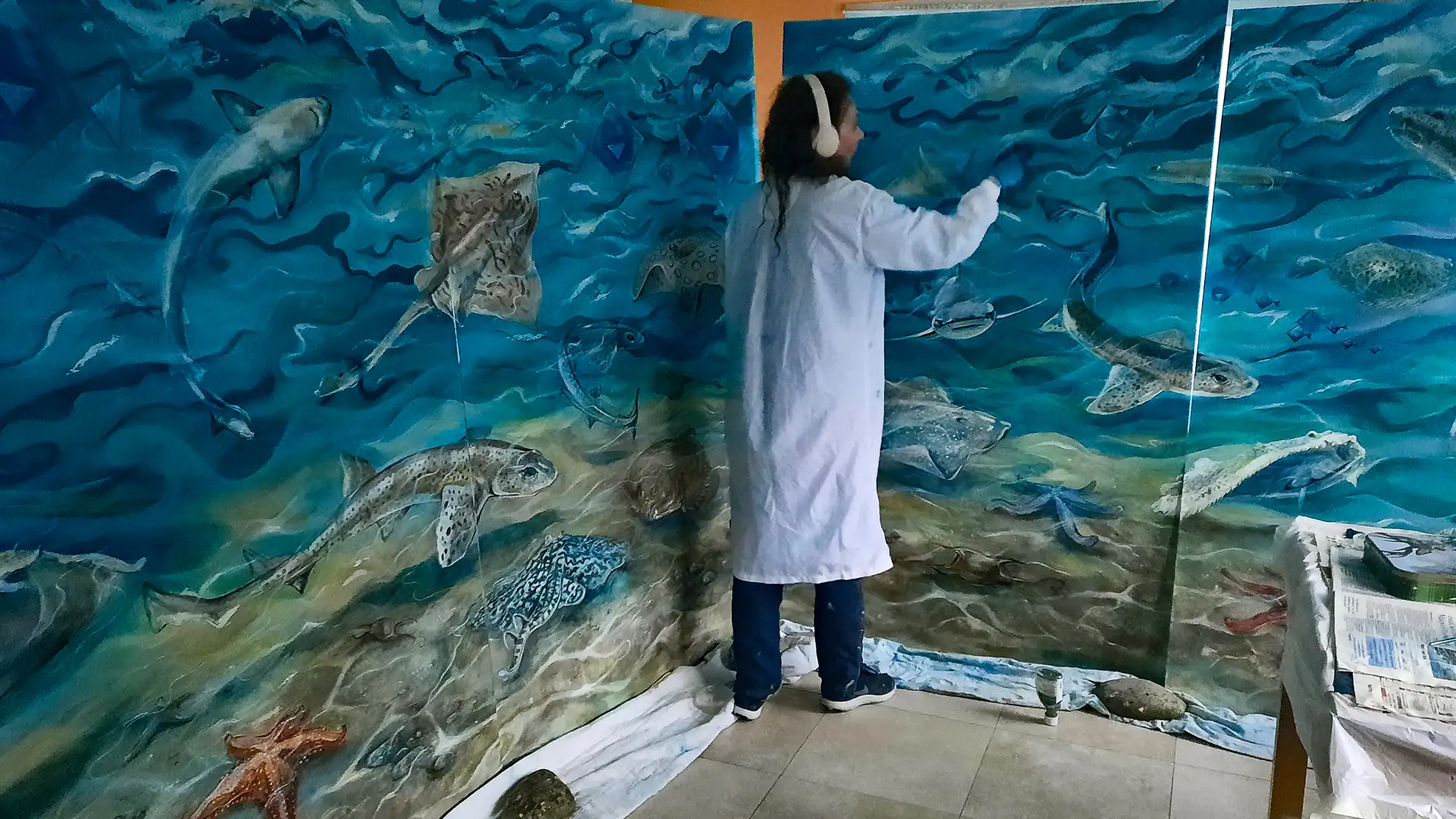 The artist working on the murals for the Aquarium